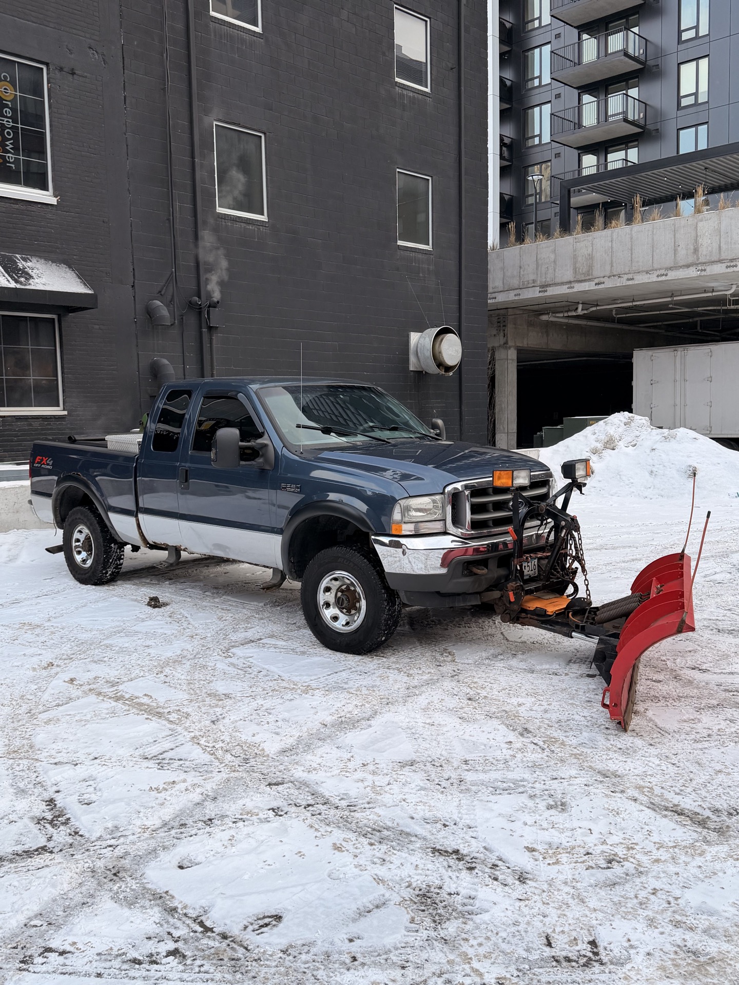 Snow plow truck with a red blade in a Twin Cities lot.
